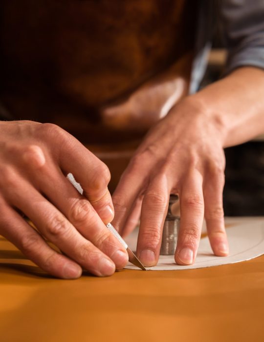 Close up of a shoemaker cutting leather in a workshop