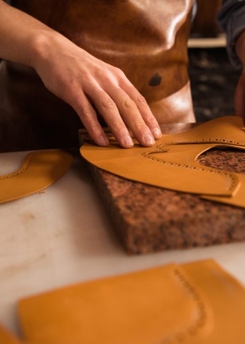 Close up of a male cobbler working with leather textile at his workplace