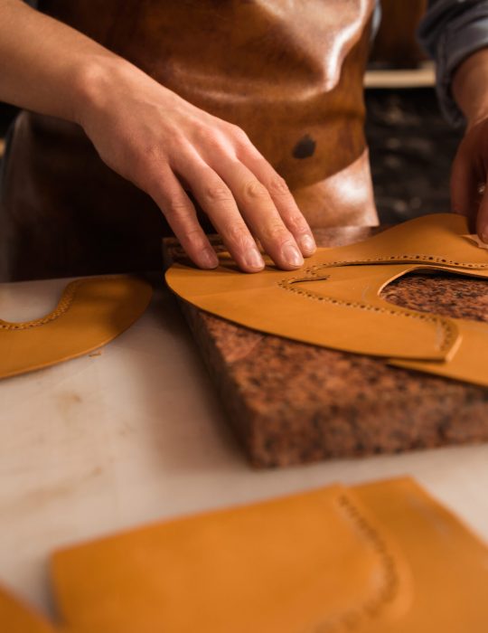Close up of a male cobbler working with leather textile at his workplace