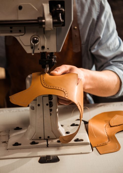 Close up of a shoemaker using sewing machine in workshop