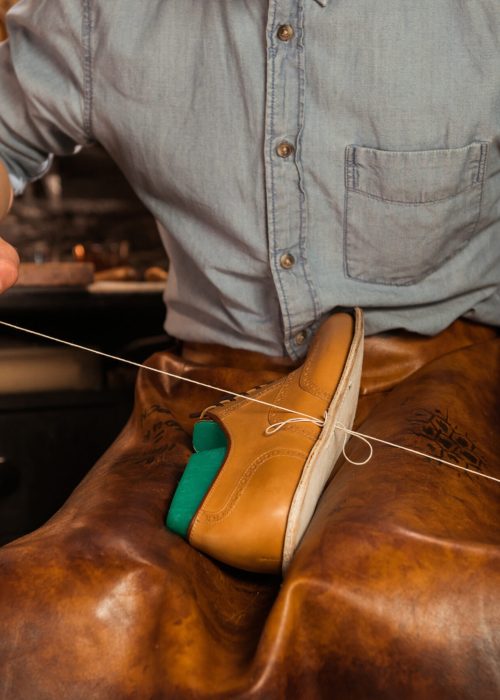 Cropped image of young shoemaker in workshop making shoes.